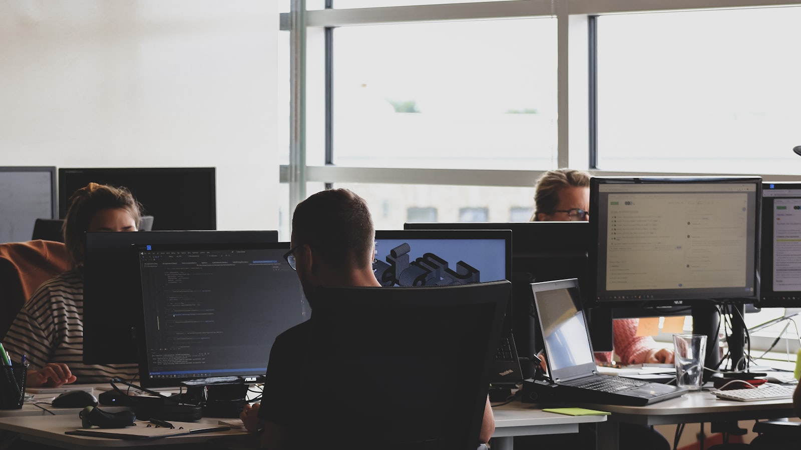 Two engineers working at adjacent screens during a code review.